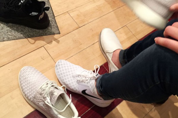 A customer tries on a pair of white Nike Roshe at Bodega, a sportswear store which fronts as a classic New York City bodega. | Photo by Siena Tauber